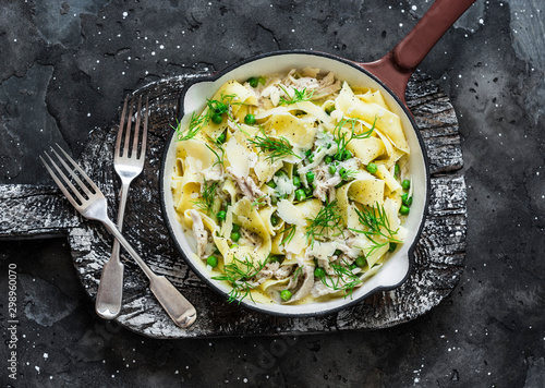 Fresh papardelle with chicken, green peas white bolognese sauce and fennel in pan on wooden rustic board on dark background, top view photo