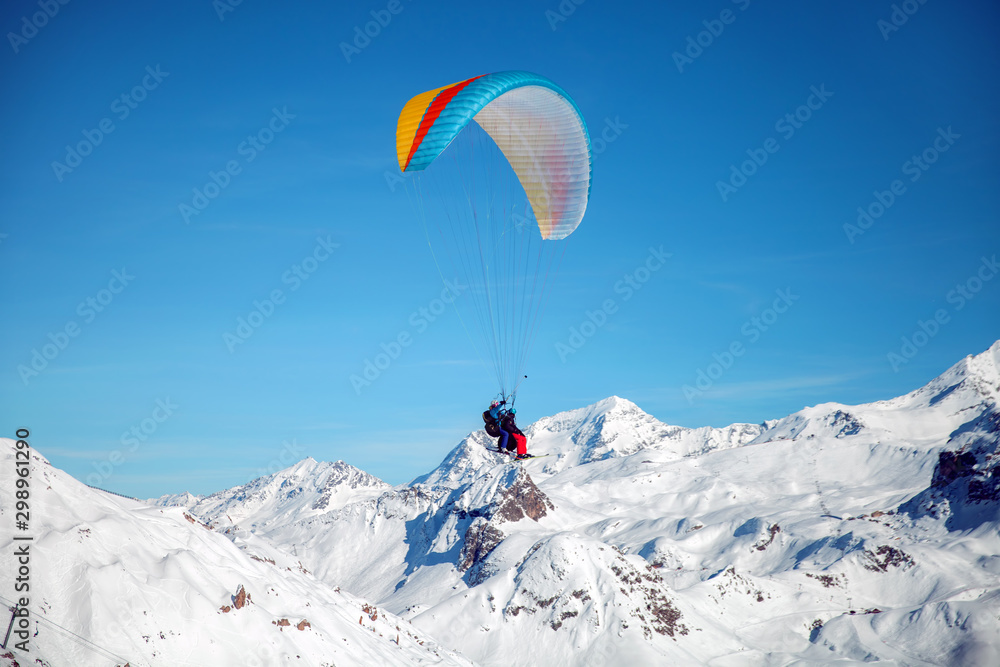 Tandem of skiers with paraglider in blue sky, France