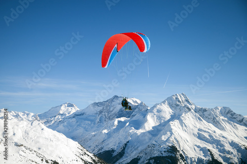 Two skiers with paraglider is flying above mountains