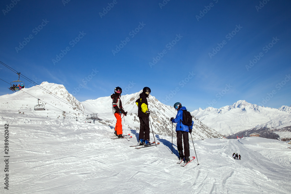 three young skiers in mirrored masks on top on a Sunny day