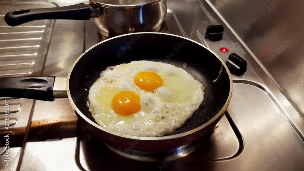Over-easy Eggs Frying in Skillet on Hot Oil on Kitchen Cooker, Close Up Over-easy Eggs Frying in Skillet on Hot Oil on Kitchen Cooker, Close Up