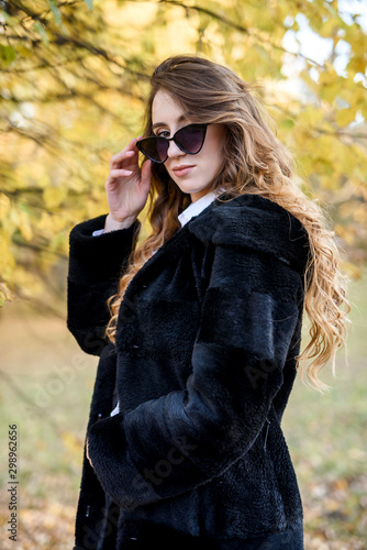 Beautiful young woman in a fur coat in the magical autumn forest.