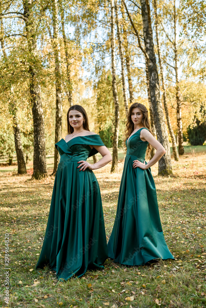 Ladies in elegant green dresses walking in autumn park. Brunette girl Dreamy young girls laughing on the outdoors Ladies in elegant green dresses walking in autumn park. Brunette girl Dreamy young girls laughing on the outdoors