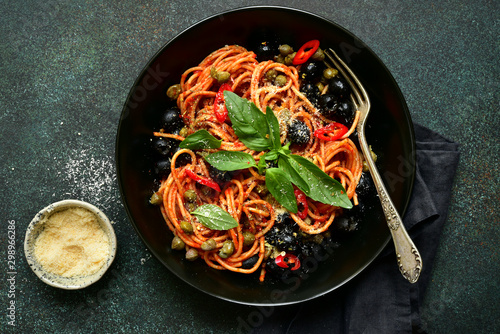 Traditional italian pasta putanesca with olives and capers in tomato sauce. Top view with copy space. photo