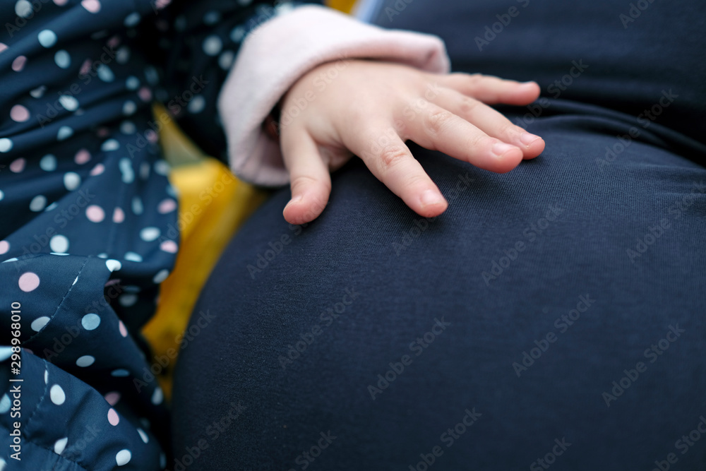 Little girl touching her pregnant mother's belly