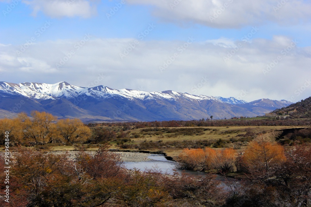 Argentina Calafate region., Patagonia.   Aprenda a pronunciar Creek crossing the valley with colorful vegetation and in the background mountains with ice-capped peaks