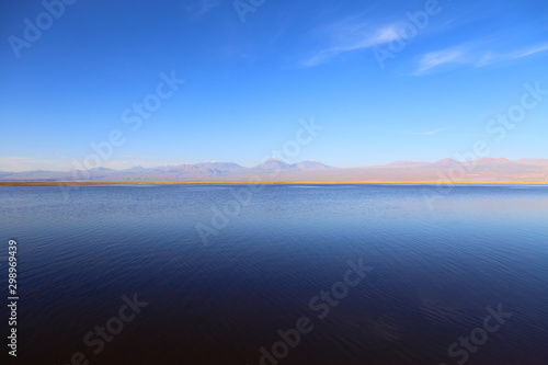 Blue lake with calm waters, in the horizon mountains and blue clean sky. Atacama desert, Chile.
