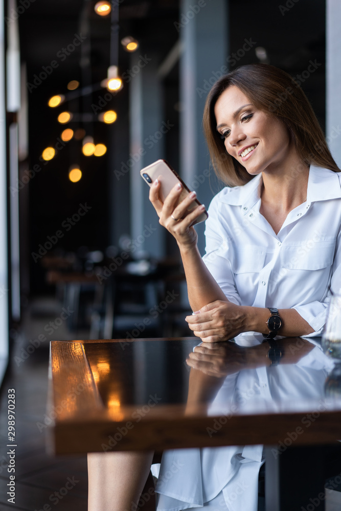 Young businesswoman using phone in coffee shop