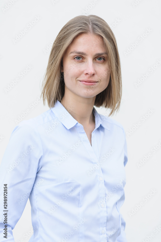 Blonde bussiness woman dressed casual with a perfect smile, standing near a white wall