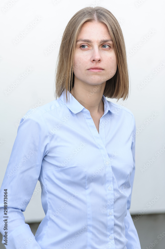 Blonde bussiness woman dressed casual with a perfect smile, standing near a white wall Blonde bussiness woman dressed casual with a perfect smile, standing near a white wall