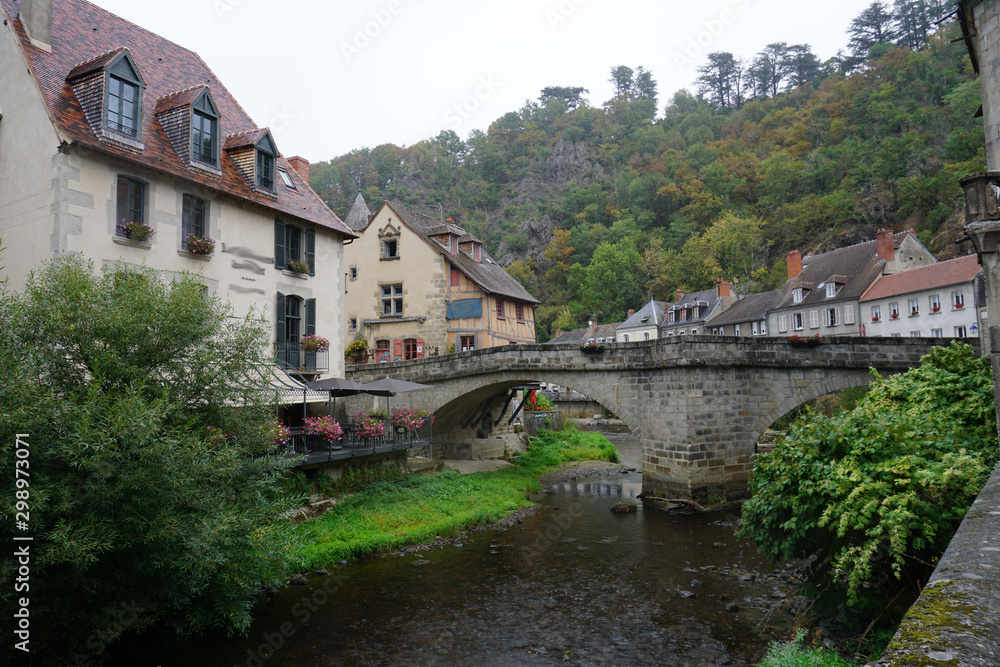 old stone bridge over the river and village in France