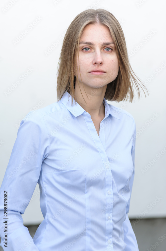 Blonde bussiness woman dressed casual with a perfect smile, standing near a white wall Blonde bussiness woman dressed casual with a perfect smile, standing near a white wall