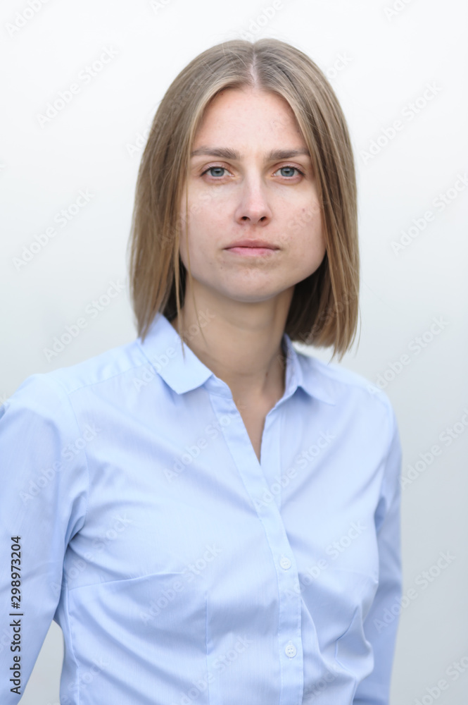Blonde bussiness woman dressed casual with a perfect smile, standing near a white wall