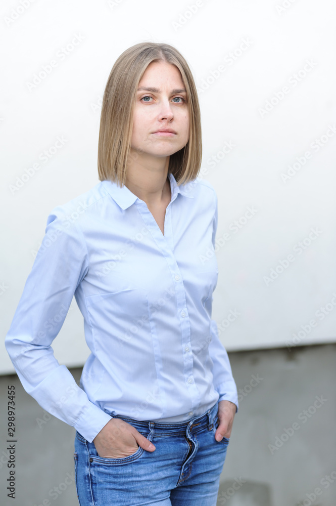 Blonde bussiness woman dressed casual with a perfect smile, standing near a white wall Blonde bussiness woman dressed casual with a perfect smile, standing near a white wall