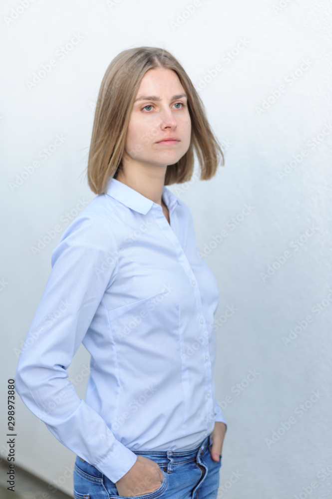 Portrait of a young successful woman working IT company on the background of the white wall Portrait of a young successful woman working IT company on the background of the white wall
