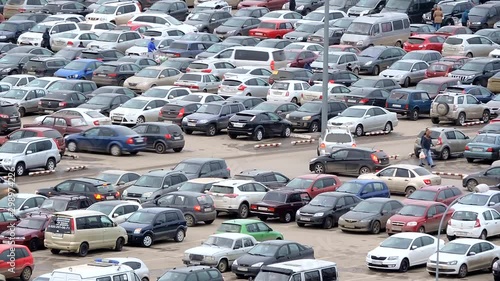 Large parking lot near the shopping center, a lot of cars and hurrying people photo