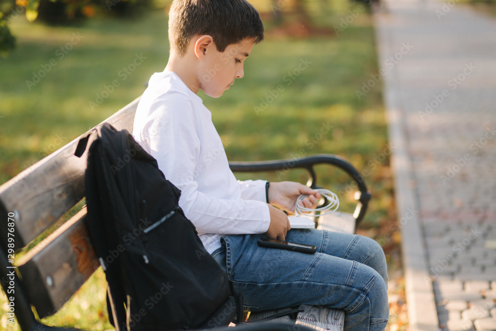 Teenage boy in white shirt use powerbank for charging his smartphone otside. Low battery on smartphone Teenage boy in white shirt use powerbank for charging his smartphone otside. Low battery on smartphone