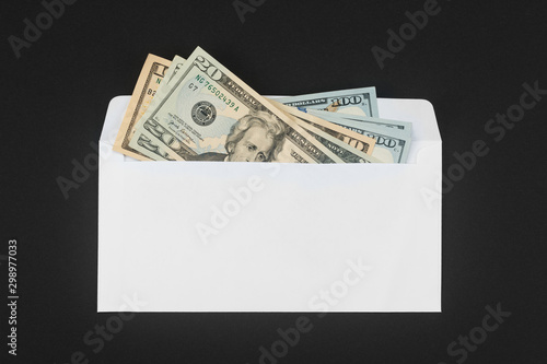 White paper envelope with money on black background and copy space for your text. Dollars in the envelope as bonus, reward, benefits concept, bribe gift. Shadow economy, illegal salary without taxes.