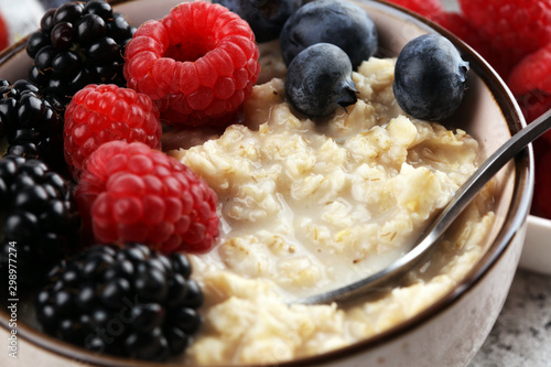 Bowl of oatmeal porridge with banana, raspberries coconut and caramel sauce on rustic table, hot and healthy food for Breakfast photo