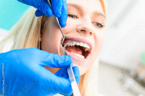 Pretty woman sitting in dental chair while professional doctor fixing her teeth