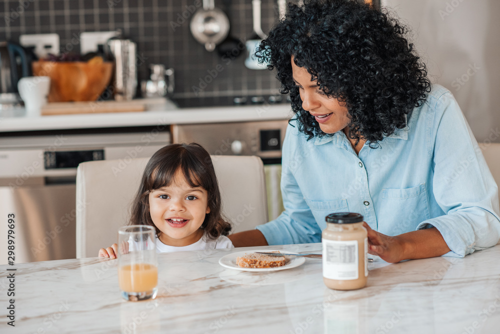 Smiling little girl eating breakfast with her mother at home Smiling little girl eating breakfast with her mother at home