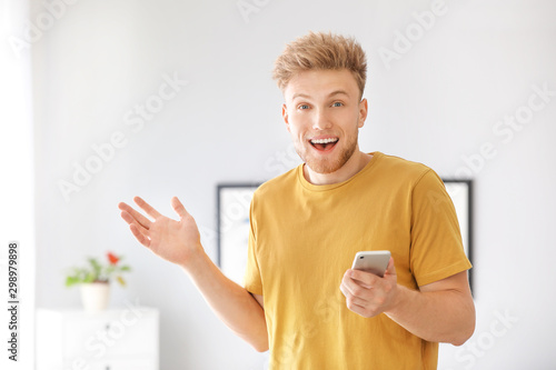 Fényképezés Portrait of happy man with mobile phone at home
