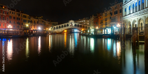 Panorama of the Grand Canal and famous Rialto Bridge or Ponte di Rialto in Venice at dark night, Italy. © Kavalenkava