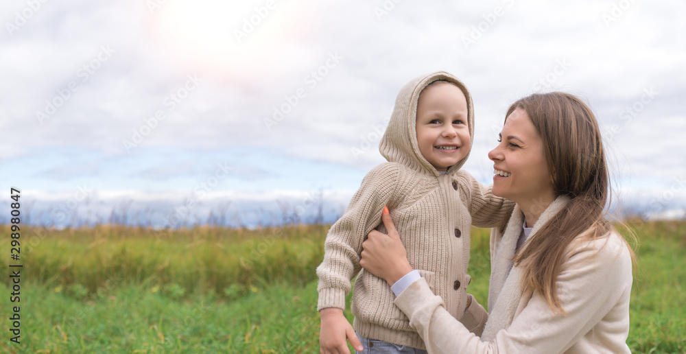 Happy family mom woman little boy weekend resting, laughing, smiling having fun playing, background green. Warm casual wear, hooded sweater. Caring support love nurturing tenderness. Free space text.