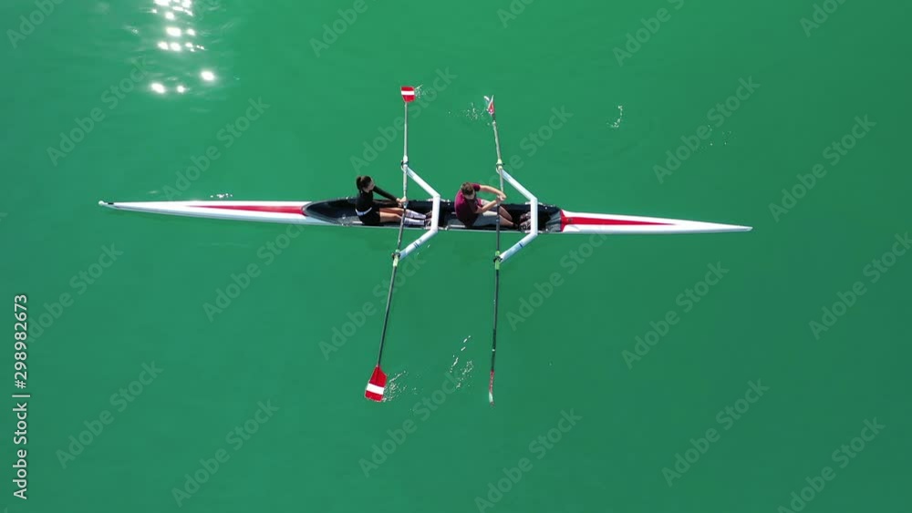 Aerial drone bird's eye view video of sport canoe operated by team of young women in deep blue sea waters Aerial drone bird's eye view video of sport canoe operated by team of young women in deep blue sea waters