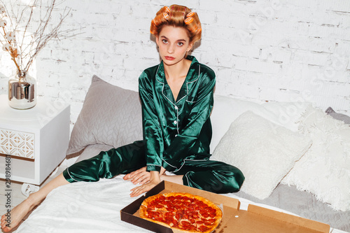 nice woman in pajamas doubting with pizza box in bed photo