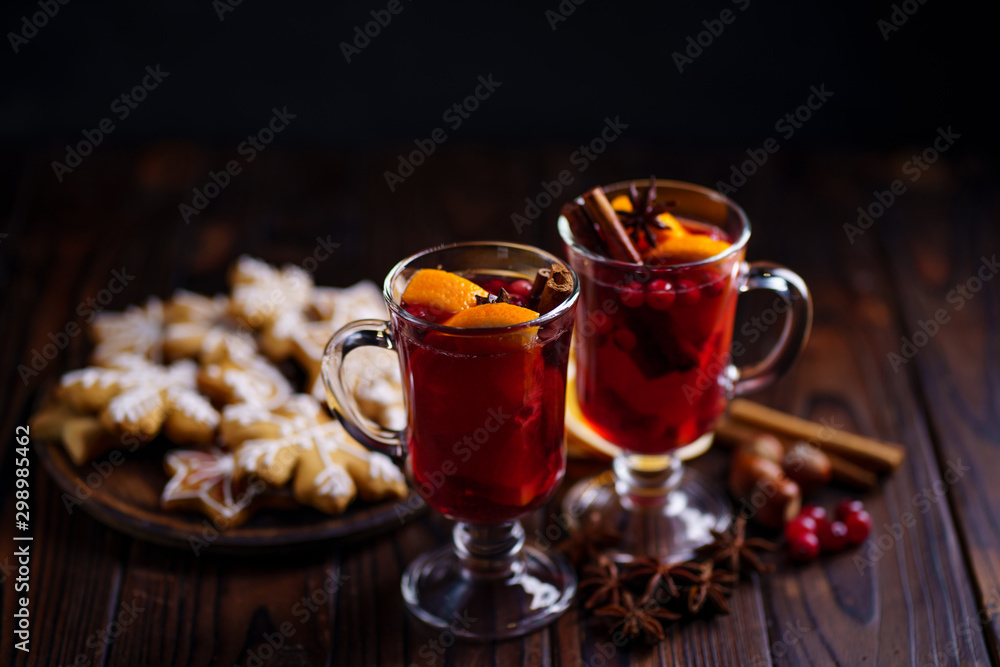 Christmas mulled wine and gingerbread cookies with spices and food decorations on dark wooden table, copy space. Christmas and New Year traditions, festive food Christmas mulled wine and gingerbread cookies with spices and food decorations on dark wooden table, copy space. Christmas and New Year traditions, festive food