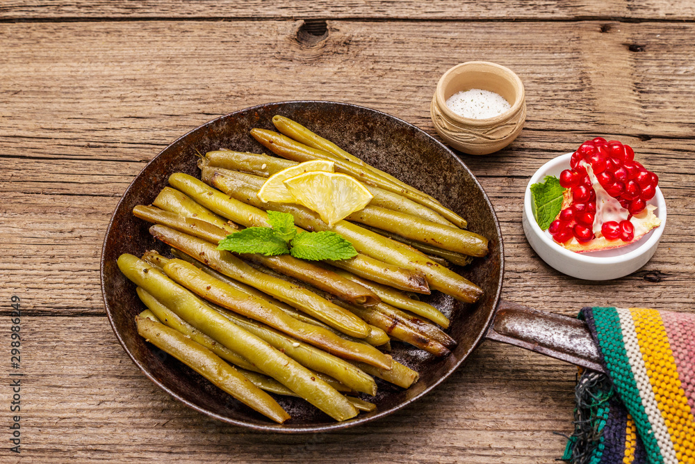 Baked green bean in pan with sesame seeds, mint and lemon. Healthy vegan (vegetarian) food concept Baked green bean in pan with sesame seeds, mint and lemon. Healthy vegan (vegetarian) food concept