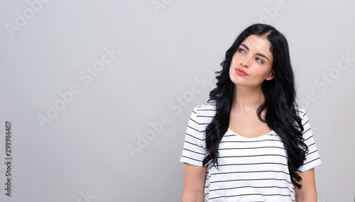 Young woman in a thoughtful pose on a gray background © Tierney