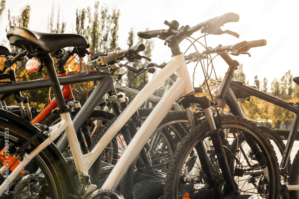 Many modern bicycles parked outdoors Many modern bicycles parked outdoors