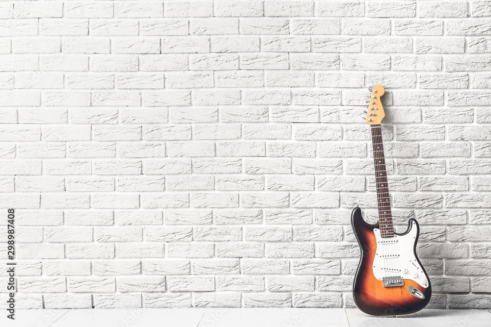 Fototapeta Nowożytna gitara basowa blisko białego ściana z cegieł