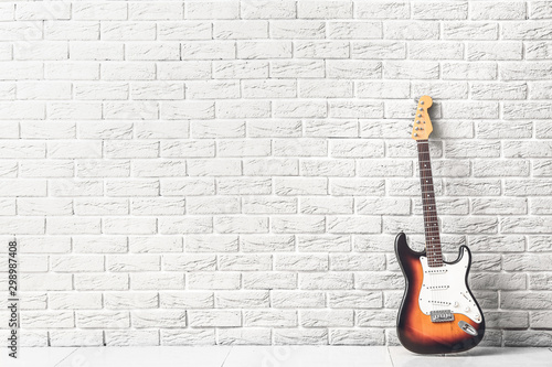 Modern bass guitar near white brick wall © Pixel-Shot