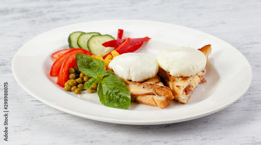 Ñrispy toast with ham and cheese, poached eggs, fresh vegetables and sauce. Ñrispy toast with ham and cheese, poached eggs, fresh vegetables and sauce.