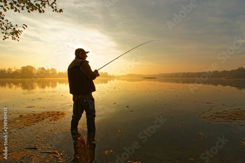 angler catching fish in the lake during cloudy sunrise photo
