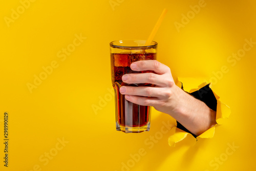 Hand holding cola with straw