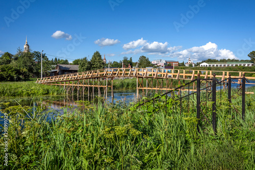 Russia, Vladimir Oblast, Golden Ring, Suzdal: Panorama view with wooden bridge over Kamenka river in one of the oldest Russian towns with famous Trading Arcades and Rizopolozhenskiy Monastery - travel photo