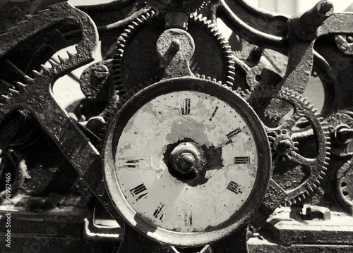ancient rusty broken iron clock with weathered face and exposed complex mechanism of cogs and gears