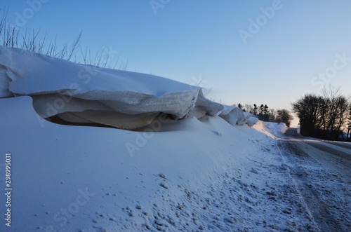 Snowdrifts near road on a cold afternoon