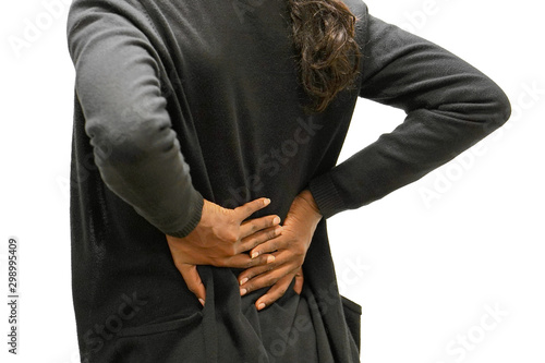 Closeup view of african woman with pain in kidneys isolated on a white background. African girl with backache clasping her hand to her lower back. Woman suffering from ribbing pain, waist pain.