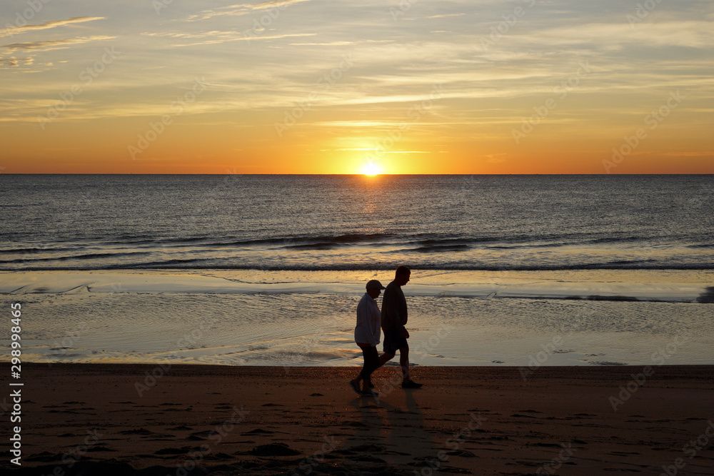 Couple walking at the beach of Tybee Island, Georgia, USA during sunrise