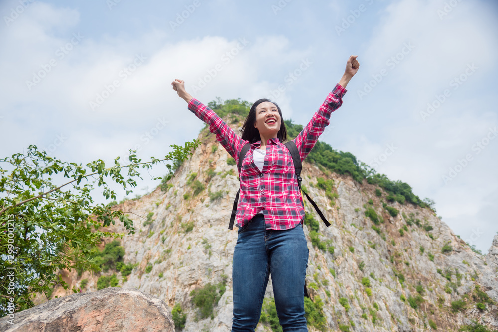 Happy asian traveller woman with backpack standing at stone hill and smiles with raising hands. Summer holiday and vacation trip , Survival travel, lifestyle concept. Happy asian traveller woman with backpack standing at stone hill and smiles with raising hands. Summer holiday and vacation trip , Survival travel, lifestyle concept.