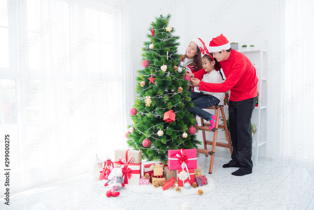 Happy asian family decorating christmas tree together at home.