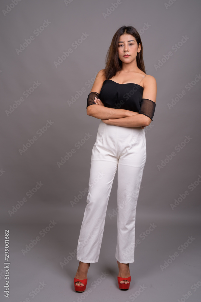 Young beautiful Asian woman against gray background Young beautiful Asian woman against gray background