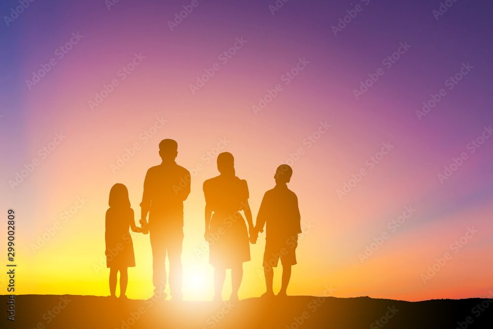 Silhouettes of father mother son and daughter playing and relaxing at sunset evening sky background. Silhouettes of father mother son and daughter playing and relaxing at sunset evening sky background.