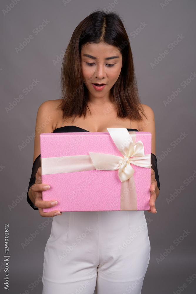 Full body shot of young beautiful Asian woman holding gift box Full body shot of young beautiful Asian woman holding gift box