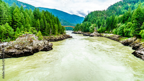 The mighty Fraser River, with the the arch shaped steel structure of the Alexandra Bridge on the Trans Canada Highway in the distance. Viewed from the upstream historic Second Alexandra Bridge photo